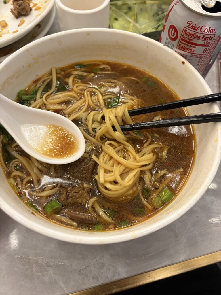 The full bowl that started it. Brisket, hand-pulled noodles, scallion — and that color that doesn't quit.